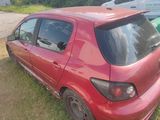 une petite voiture rouge garée dans l'herbe à côté d'une voiture verte