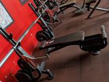 a row of exercise equipment in a gym with a red wall