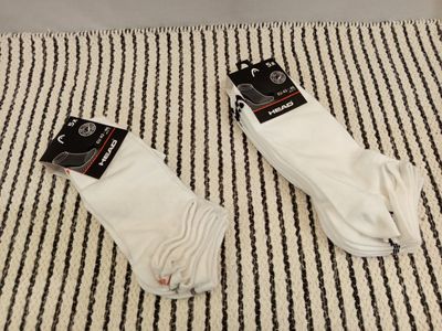 two pairs of white socks sitting on top of a black and white striped blanket
