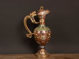 an image of a gold and green vase sitting on top of a wooden table