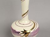 un vase blanc orné d'un motif violet et doré