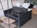une photo d'un salon avec un canapé noir et un lavabo blanc