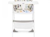 la chaise haute est blanche et est équipée d'un siège pour bébé