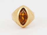 a close up of a gold ring with a faceted citrine stone