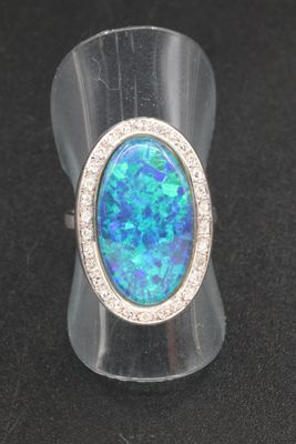 an oplite and diamond ring on a black surface