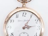 une image d'une montre de poche en gros plan sur une surface blanche