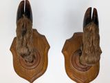 pair of wooden animal heads mounted on a wooden plaque