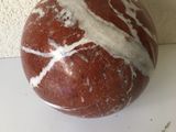 une boule en marbre rouge et blanche posée sur une table