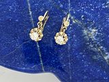 une paire de boucles d'oreilles en diamant posée sur une dalle de pierre bleue