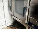un four argenté posé dans une cuisine, à côté d'une cuisinière