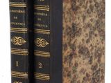an old book sitting on top of a white table next to a pair of books