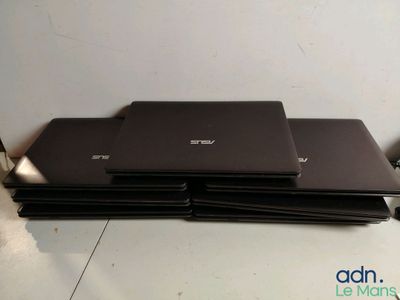Plusieurs ordinateurs portables sont empilés les uns sur les autres sur une table