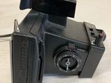 a black polaroid camera sitting on a white surface