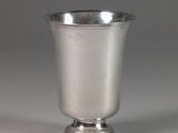une coupe en argent ancienne posée sur une table blanche