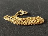 a close up of a gold chain bracelet on a black surface
