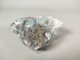 crystal cluster with blue and white crystals sitting on a white surface