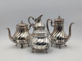 three silver teapots and a sugar bowl on a table
