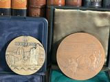 a gold medal sitting in a case in front of a row of books