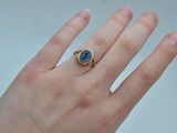 an image of a woman ' s hand holding a ring with a blue stone on it
