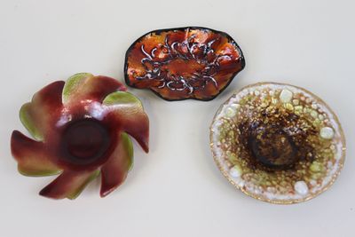 trois petits plats posés sur une table blanche, avec une fleur rouge au centre
