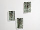 trois morceaux de verre vert sur un mur blanc, avec un fond blanc