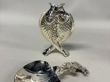 two silver spoons with a bird on them sitting next to each other