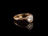 un gros plan d'une bague en or sertie d'un diamant, posée sur une surface noire