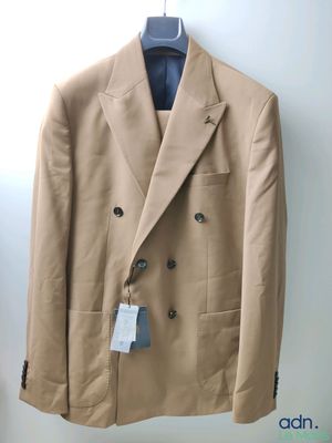 beige jacket hanging on a hanger in a room with a white wall