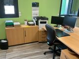 a desk with two monitors and a printer in the corner