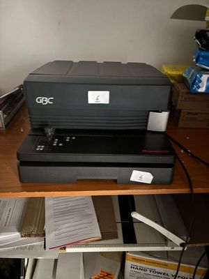 une imprimante posée sur un bureau, à côté d'une pile de papiers
