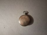 a silver pocket watch on a table with a white background