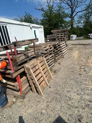 un homme qui se tient à côté d'un tas de palettes