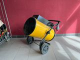a yellow cement mixer sitting on the floor next to a red wall