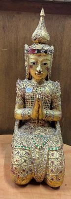 une statue représentant une personne assise sur une table en bois