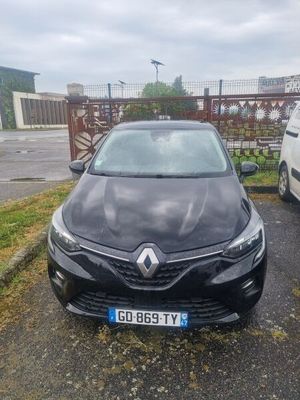 La voiture noire est garée sur le parking, à côté de la camionnette blanche.
