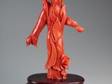 a red carved figurine of a woman on a stand