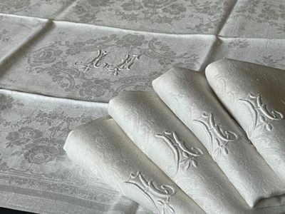 four folded napkins on a table with a monogram on them