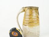 a measuring tape in front of a brown and white pitcher