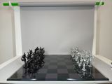 a black and white chess board with silver chess pieces on it