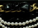 pearl necklace with gold chain and black bow on black surface
