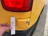 a person holding a ruler in front of a yellow car