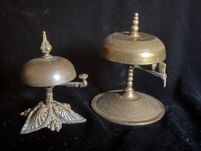deux bougeoirs anciens en laiton et une cloche sur fond noir