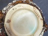 a person holding a brown and white bowl on a table