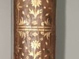 un vase doré sur une table blanche avec un ruban marron