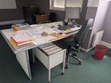 a desk with a lot of papers on it and a chair
