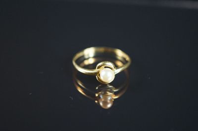 Gros plan sur une bague en or ornée d'une perle