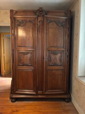 a large wooden armoire in the corner of a room