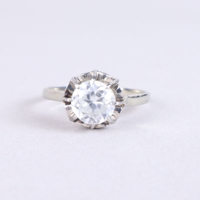 un gros plan d'une bague sertie d'un diamant blanc sur une surface blanche
