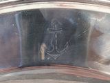 a close up of a silver plate with an anchor on it