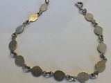 gros plan d'un bracelet en argent sur une surface blanche